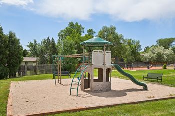 A playground with a green slide and a wooden structure.